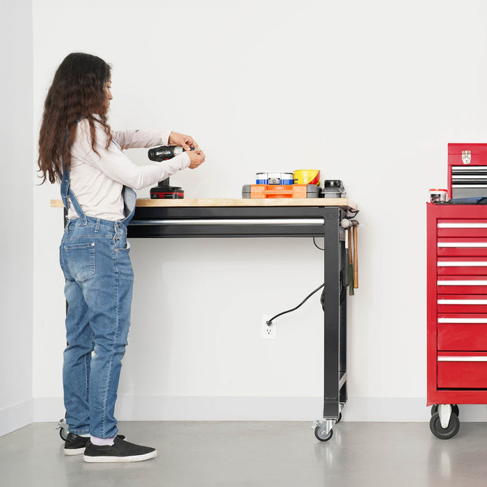 Woman adjusting a drill on a workbench with a red toolbox in the background