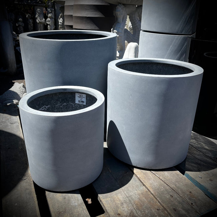 Set of gray lightweight concrete cylinder-shaped planters on a wooden surface