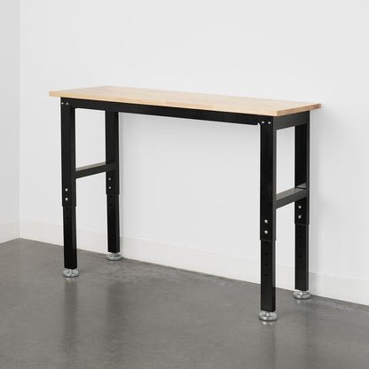 Wooden workbench with black metal legs on a concrete floor against a white garage wall.