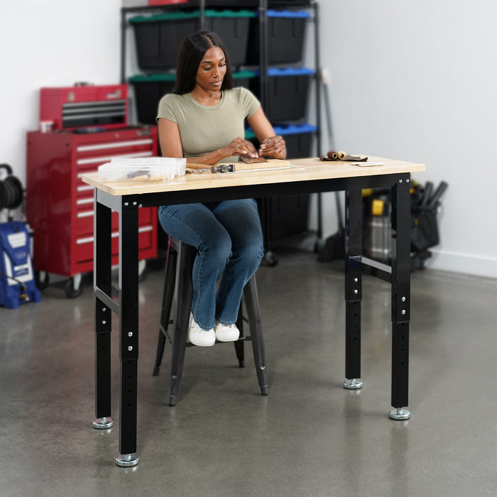 Woman working on a wooden workbench in a workshop setting.